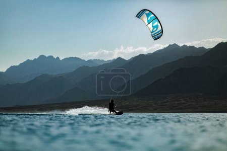 Foto de Una vista panorámica de un kitesurfista deslizándose sobre el agua de la laguna - Imagen libre de derechos