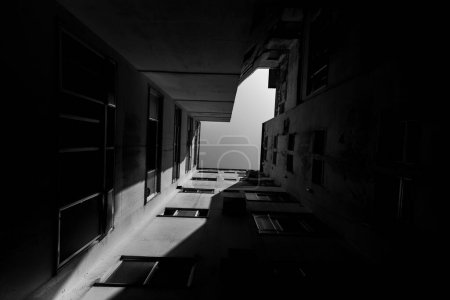 Photo for A low angle of an apartment building in shadows and sunlight against the sky shot in grayscale - Royalty Free Image