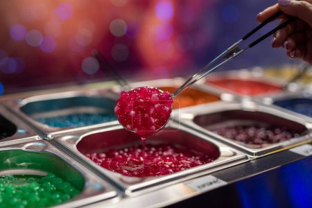 Eine Nahaufnahme einer Hand schöpft rotes Kaviar-Essen von ausgestellten Stangen, die im Restaurant zum Verkauf stehen
