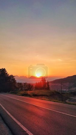 Foto de Una toma vertical de una hermosa puesta de sol brillante sobre la carretera - Imagen libre de derechos