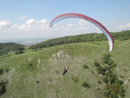Foto de Un parapente volando sobre montañas pintorescas cubiertas de vegetación - Imagen libre de derechos