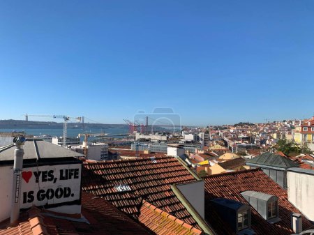 Téléchargez les photos : Une citation motivante sur le toit d'un bâtiment avec l'horizon de Lisbonne en arrière-plan. Portugal. - en image libre de droit