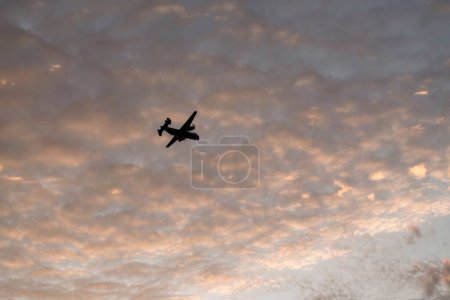 Foto de Una silueta de un avión militar volando en las nubes al atardecer en Coronado, San Diego. - Imagen libre de derechos