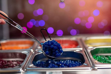 Téléchargez les photos : Un gros plan d'une cuillère à main bleu nourriture caviar à partir de poteaux affichés - en image libre de droit