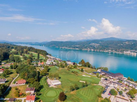 Téléchargez les photos : Une vue aérienne du rivage ensoleillé avec des bâtiments du lac Worthersee en Autriche - en image libre de droit