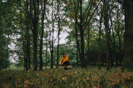 Téléchargez les photos : Vue de dos d'un randonneur vêtu d'une veste orange marchant dans une forêt d'automne - en image libre de droit