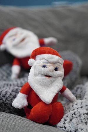 Foto de Un disparo vertical de un pequeño juguete de Santa Claus sentado en un sofá - Imagen libre de derechos