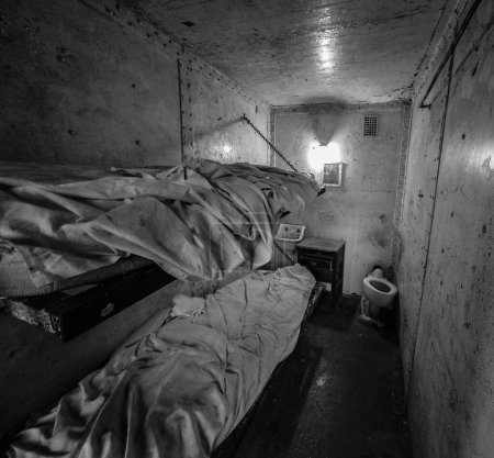 Téléchargez les photos : Une échelle de gris d'une cellule de prison avec des murs fissurés et des conditions de vie horribles, angle élevé - en image libre de droit
