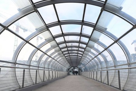 Foto de Perspectiva atenuante del moderno puente cubierto en forma de arco con personas en la ciudad - Imagen libre de derechos