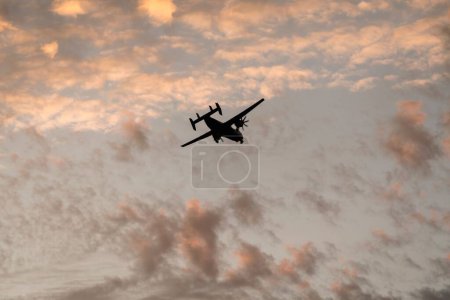 Photo for A low angle shot of a silhouette of the Coronado San Diego military airplane flying in a sunset sky - Royalty Free Image
