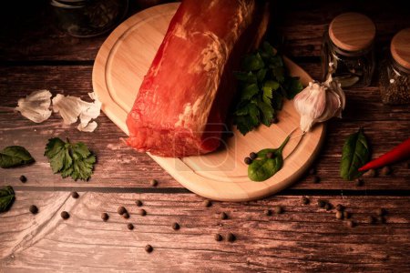 Foto de Un primer plano de deliciosa carne ahumada en una tabla de madera junto a ingredientes orgánicos frescos - Imagen libre de derechos