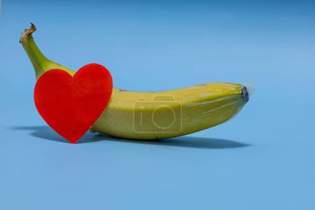 Foto de Corazón de papel rojo cerca del plátano sobre un fondo azul - Imagen libre de derechos