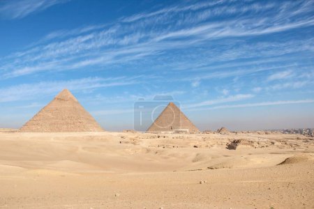 Téléchargez les photos : Les pyramides égyptiennes antiques contre un ciel nuageux bleu par une journée ensoleillée - en image libre de droit