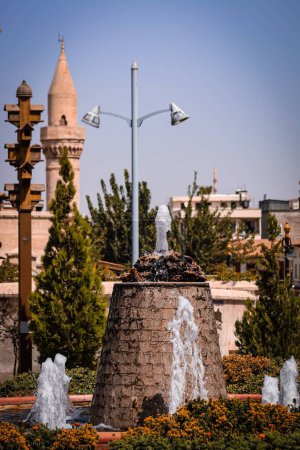 Photo for A vertical view of a beautiful fountain surrounded by colorful flowers in a city - Royalty Free Image