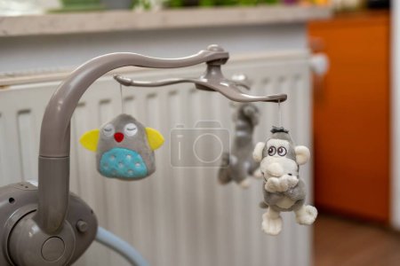 Foto de Un primer plano de cuna musical de bebé gris con pequeños juguetes de peluche sobre fondo borroso - Imagen libre de derechos
