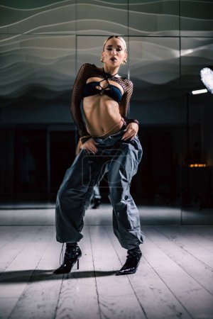 Foto de Una foto vertical de una hermosa bailarina posando en top de malla superpuesta en pantalones negros y holgados - Imagen libre de derechos