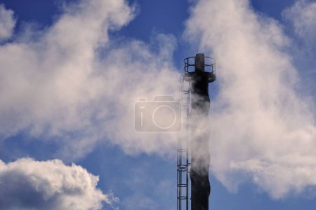 Téléchargez les photos : Une cheminée industrielle avec un ciel bleu nuageux en arrière-plan - en image libre de droit