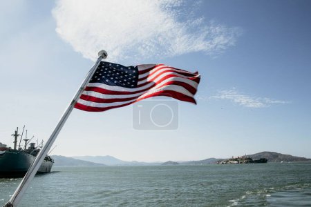 Foto de La bandera de América ondeando en el viento, y el mar en el fondo - Imagen libre de derechos