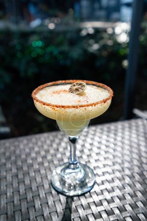 Photo for A spicy yellow margarita with garnished rim and lemon at an outdoor restaurant cocktail bar - Royalty Free Image