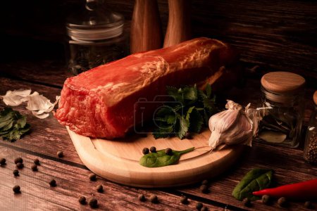 Téléchargez les photos : Un gros plan de viande fraîche savoureuse sur une table en bois avec ajout d'herbes fraîches et d'épices aromatiques - en image libre de droit