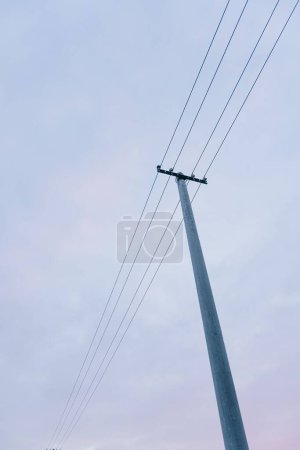 Foto de Una toma vertical de ángulo bajo de una torre de electricidad alta con cables en un cielo azul - Imagen libre de derechos