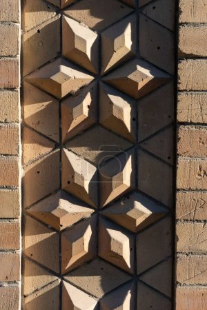 Foto de Un plano vertical de la pared de ladrillo de piedra tallada en forma de flor en un día soleado - Imagen libre de derechos