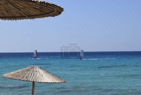 Foto de Un selectivo de sombrillas de playa frente a los surfistas en el mar - Imagen libre de derechos
