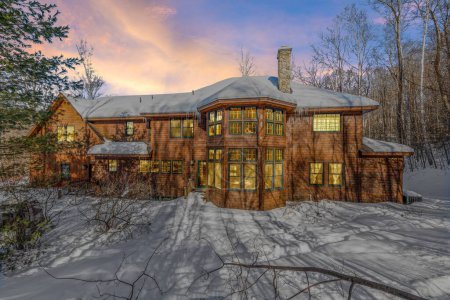 Téléchargez les photos : Une belle maison rustique contemporaine en bois dans les montagnes enneigées en soirée - en image libre de droit