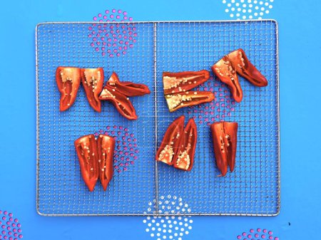 Photo for A top view of red Espelette peppers placed on a grid on the blue background - Royalty Free Image