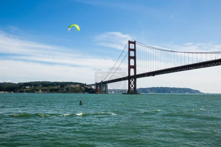 Foto de Una hermosa toma de una persona deslizándose en las aguas onduladas y el puente Golden Gate en el fondo - Imagen libre de derechos