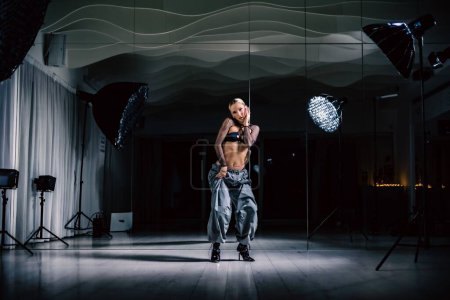 Téléchargez les photos : Une belle danseuse posant en mesh overlay crop top en pantalon noir et baggy dans un studio - en image libre de droit