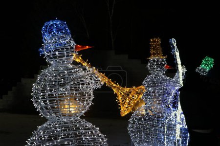 Téléchargez les photos : Deux bonhommes de neige décoratifs avec des instruments de musique sur fond sombre - en image libre de droit