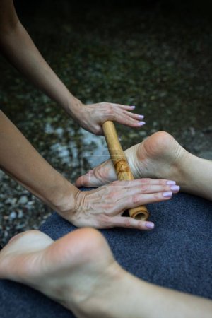 Téléchargez les photos : Un plan vertical d'un massage professionnel relaxant des pieds avec un bâton de bois - en image libre de droit