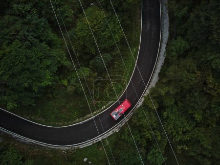 Téléchargez les photos : Une belle vue de dessus depuis un drone d'une route bouclée avec un ven rouge entouré d'arbres en Slovénie - en image libre de droit
