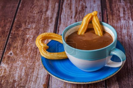 Téléchargez les photos : Chocolat chaud avec un churro en forme de coeur sur une table en bois - en image libre de droit