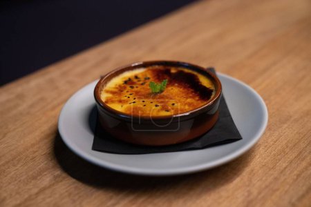 Photo for A creme brulee with mint leaves on top of caramelized sugar top layer at a restaurant in a clay bowl - Royalty Free Image