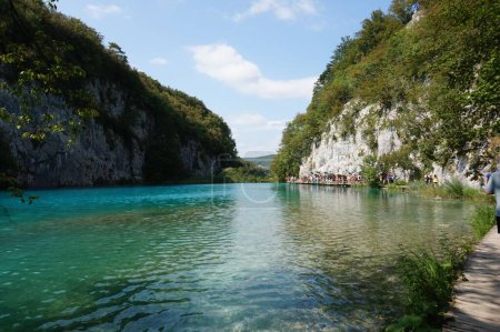 Foto de Un lago azul todavía rodeado de acantilados rocosos y plantas verdes en el Parque Nacional de los Lagos de Plitvice - Imagen libre de derechos