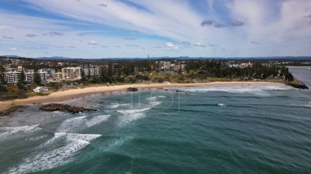 Malerischer Blick auf den Town Beach in Port Macquarie, NSW, mit grünen Bäumen und Gebäuden an der sandigen und felsigen Küste
