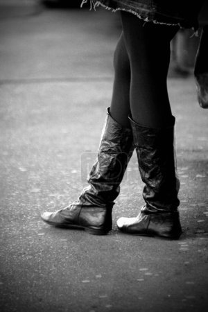 Photo for A vertical grayscale closeup of a girl wearing black leather boots. - Royalty Free Image