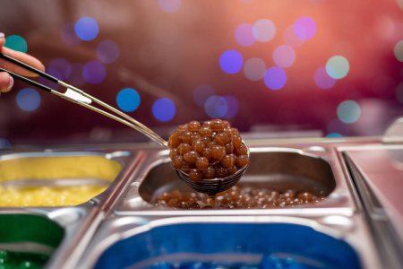 Téléchargez les photos : Un gros plan d'une pelle à main brun oeufs Caviar nourriture à partir de poteaux affichés - en image libre de droit