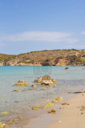 Téléchargez les photos : Un plan vertical de rochers sur la mer près de la plage et une falaise en arrière-plan sous le ciel bleu - en image libre de droit