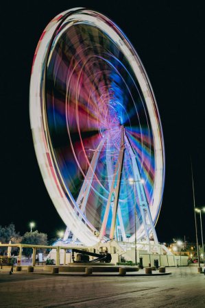 Téléchargez les photos : Une longue exposition verticale d'une grande roue la nuit avec des lumières colorées à Rimini, Italie - en image libre de droit