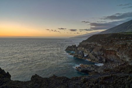 Foto de Un hermoso paisaje de acantilados rocosos frente al mar al atardecer - Imagen libre de derechos
