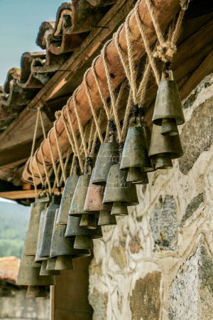 Téléchargez les photos : Plan à angle bas de vieilles cloches métalliques accrochées à une corde sur le toit d'un bâtiment en pierre - en image libre de droit