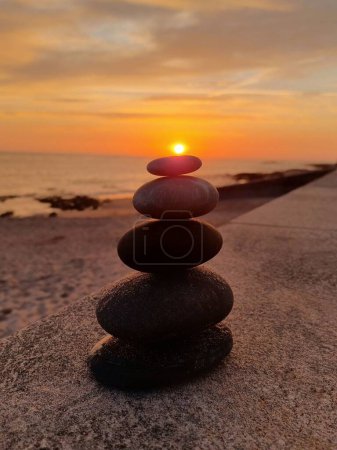 Téléchargez les photos : Une pile de rochers les uns sur les autres sur la plage au coucher du soleil - en image libre de droit