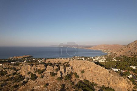 Photo for An aerial view of a town on the rocky shore with a blue sky in the background, Rhodes, Greece - Royalty Free Image