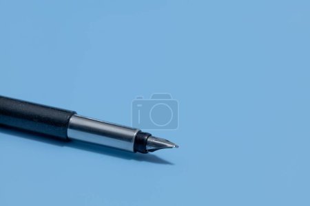Photo for A closeup shot of a vector pen with a black plastic body and metal accents on a blue background - Royalty Free Image