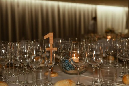 Téléchargez les photos : Un gros plan de verres à vin sur une table de dîner à une fête avec un signe numérique - en image libre de droit