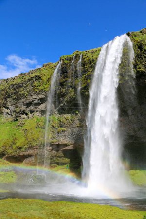 Téléchargez les photos : Un beau paysage de cascade Seljalandsfoss avec le reflet de l'arc-en-ciel à la lumière du jour en Islande - en image libre de droit