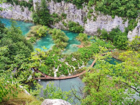 Téléchargez les photos : Vue aérienne d'un sentier en bois au-dessus d'un lac bleu entouré d'arbres, parc national des lacs de Plitvice - en image libre de droit